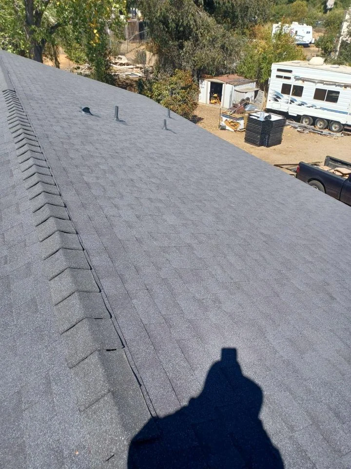 Gray asphalt shingle roof with ridge vent and metal flashing installed on residential home