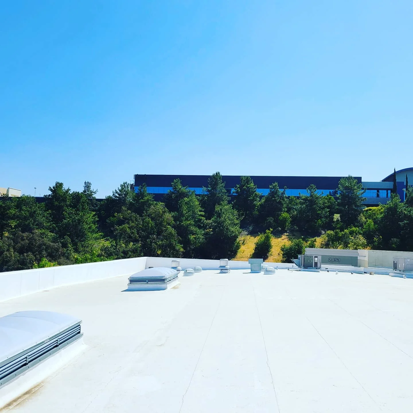 White flat roof with HVAC units and skylights on commercial building in San Diego
