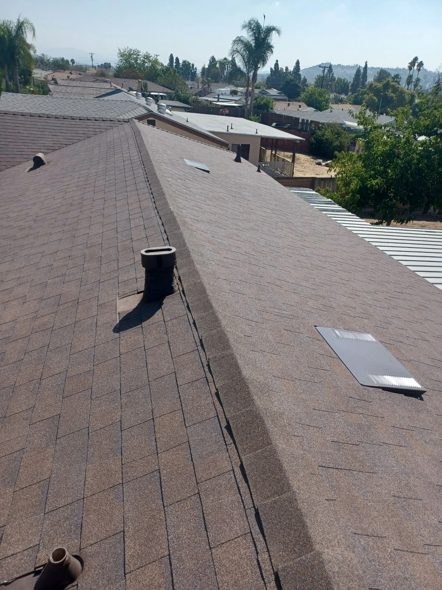 Newly installed gray asphalt shingle roof with vents and flashing on residential home