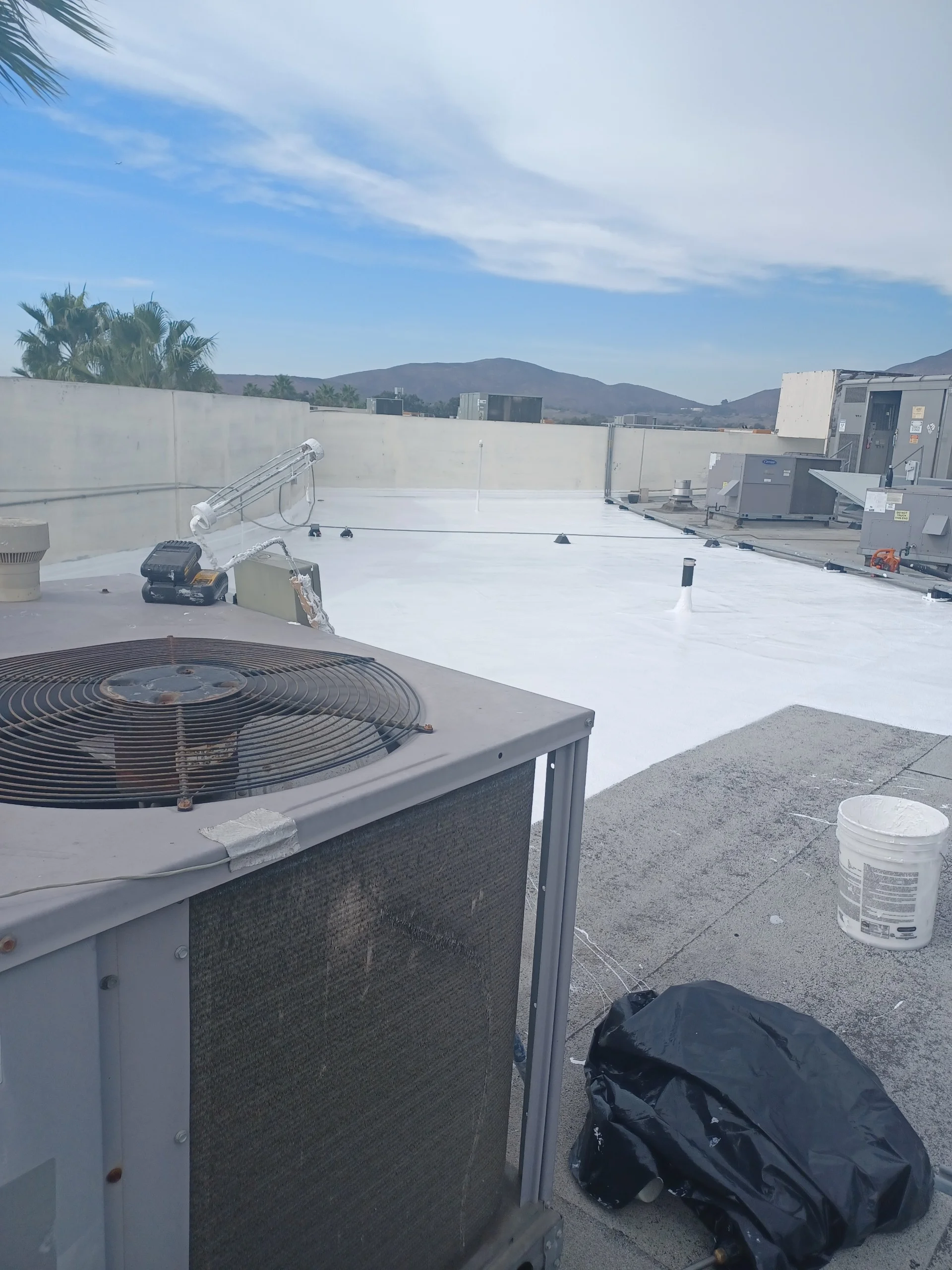 White flat roof membrane installation with HVAC unit and parapet walls on commercial building