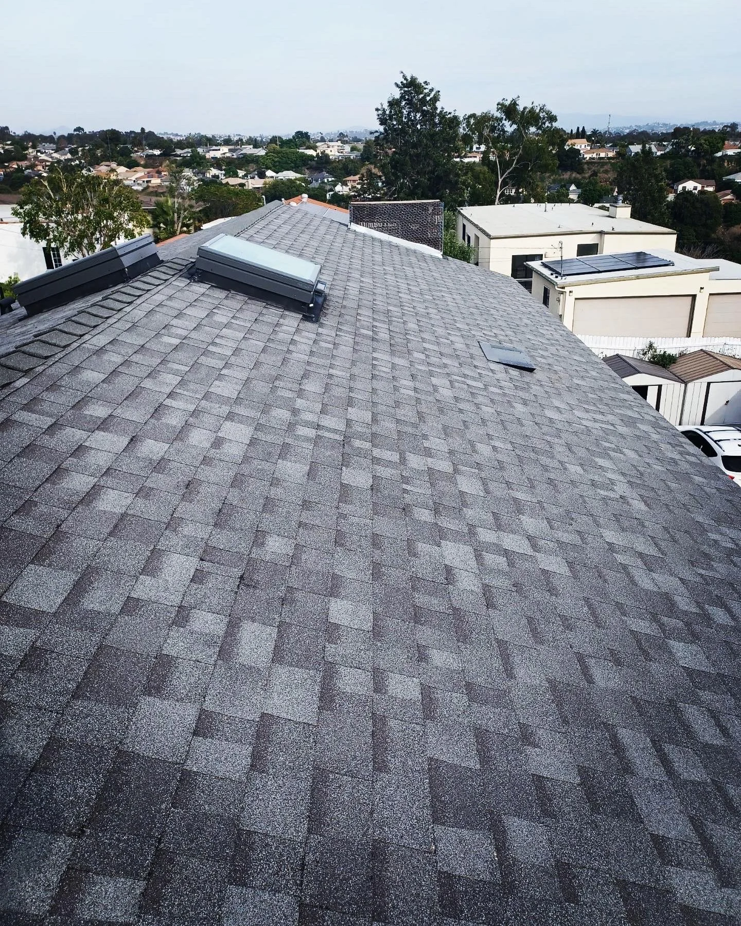 New gray architectural shingle roof with skylight and proper flashing installation