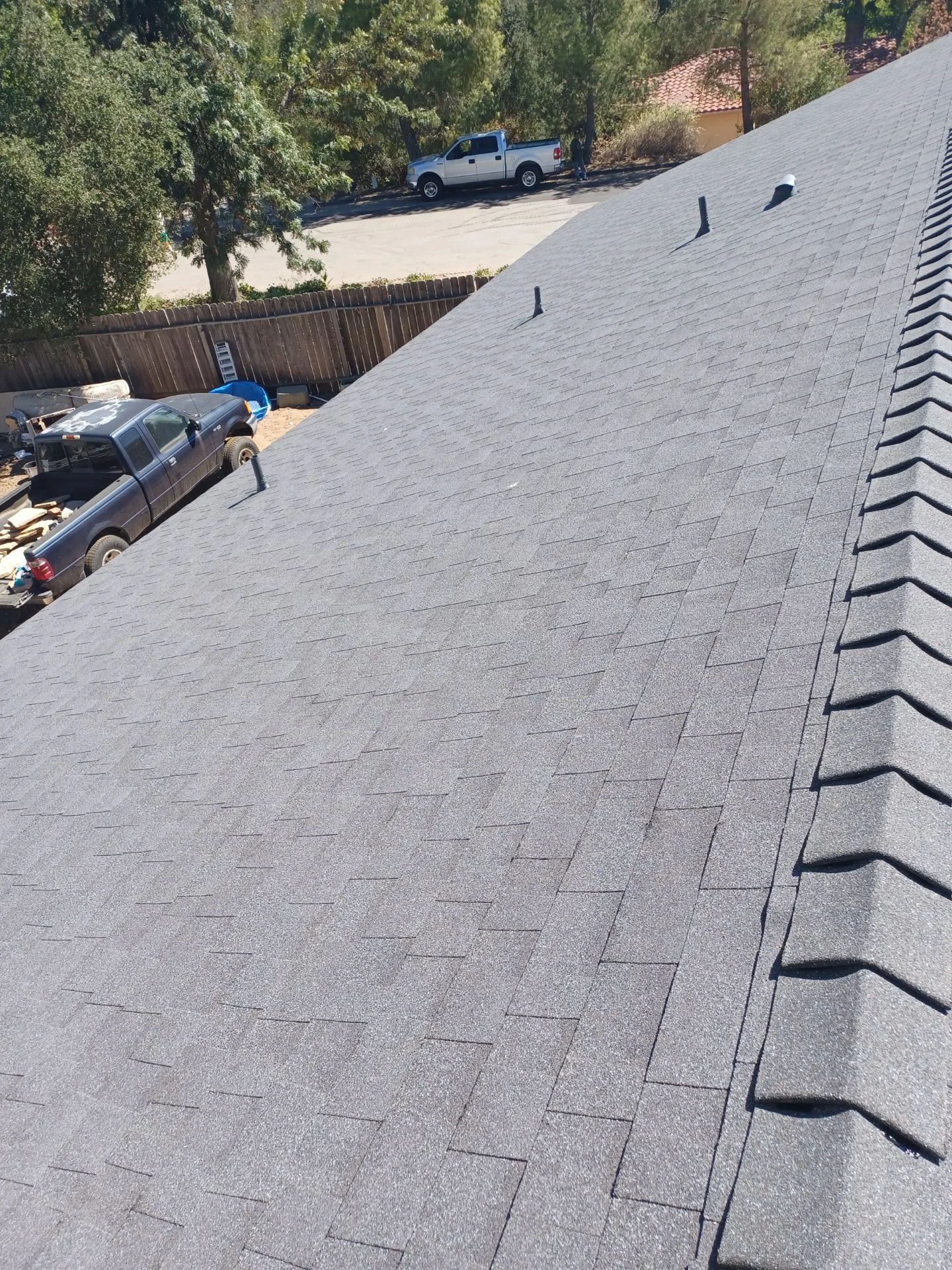 New gray asphalt shingle roof with ridge vents and proper installation on residential home