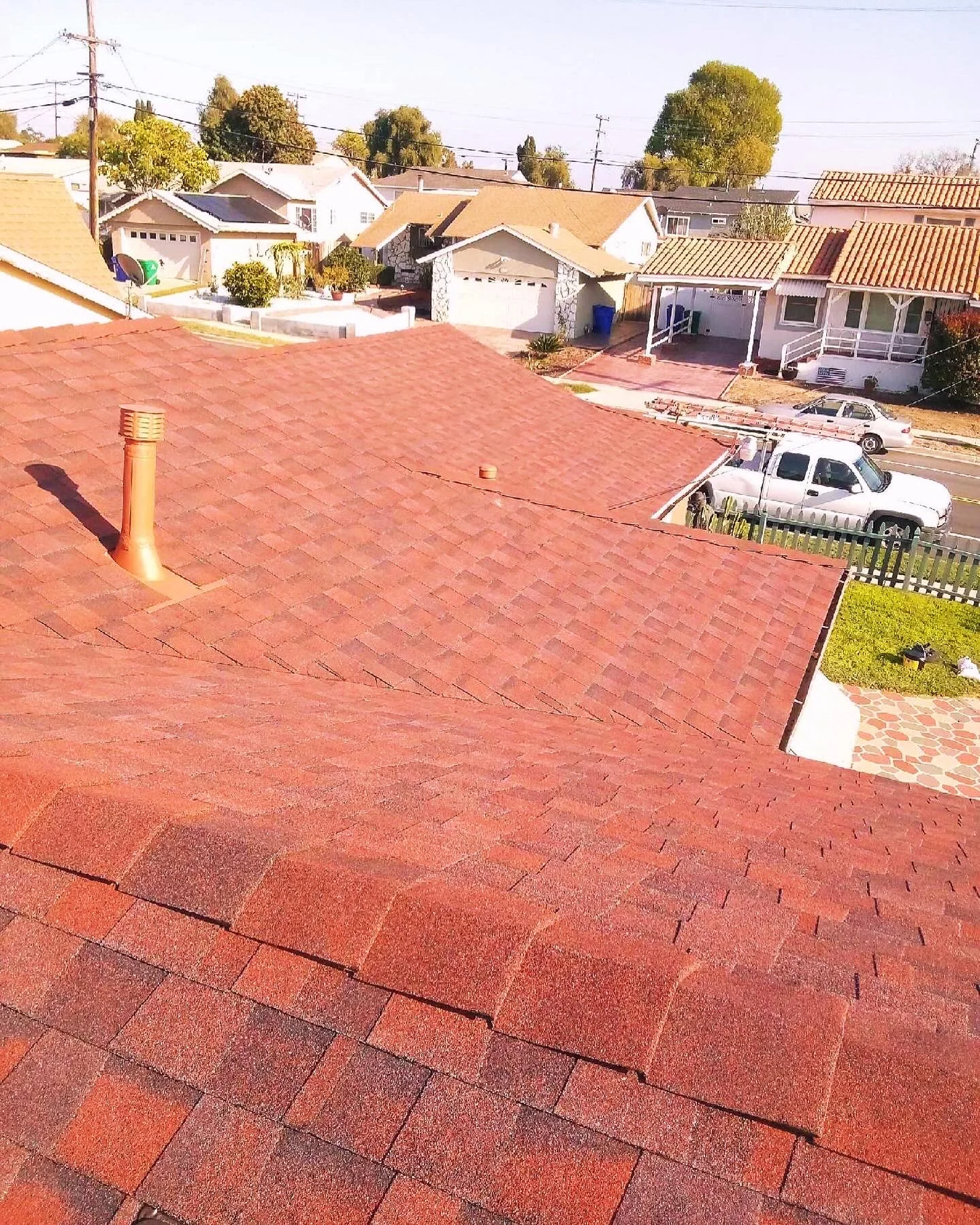 Newly installed terra cotta asphalt shingle roof with visible nailing pattern and proper ventilation