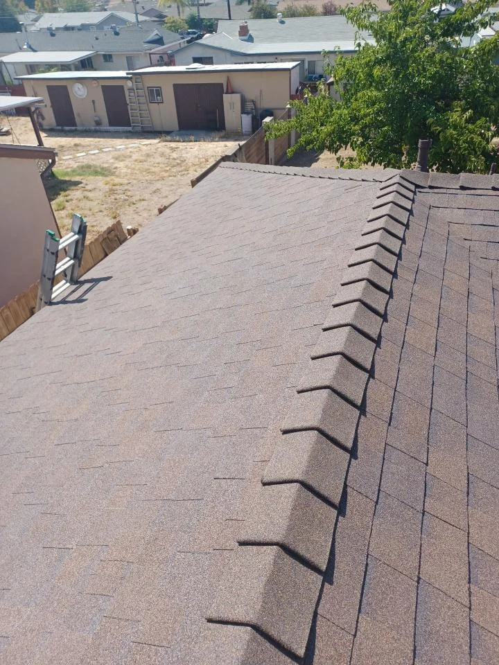 Newly installed gray asphalt shingle roof with ridge vents and proper fastening pattern
