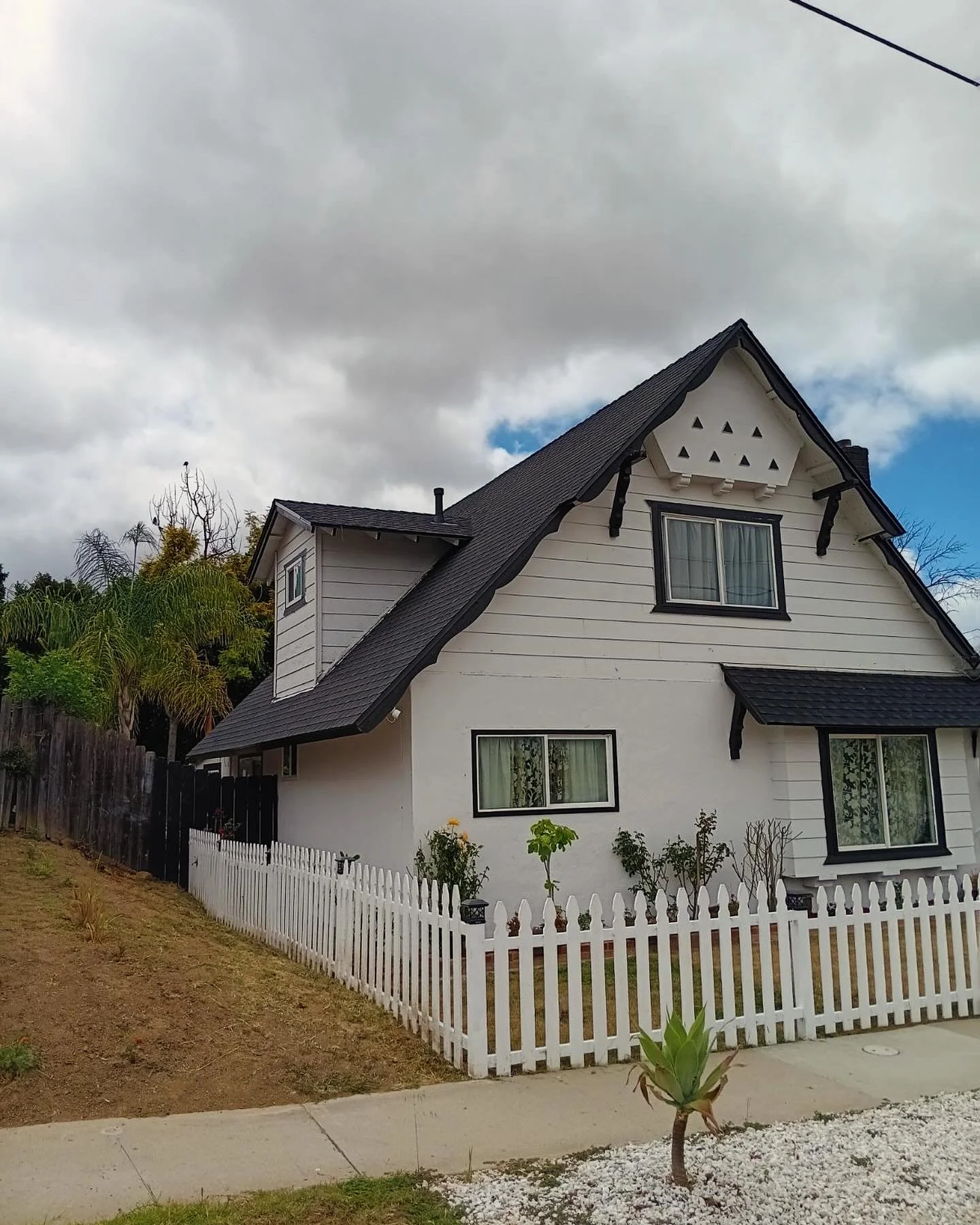 Two-story home with new black architectural shingle roof and white picket fence