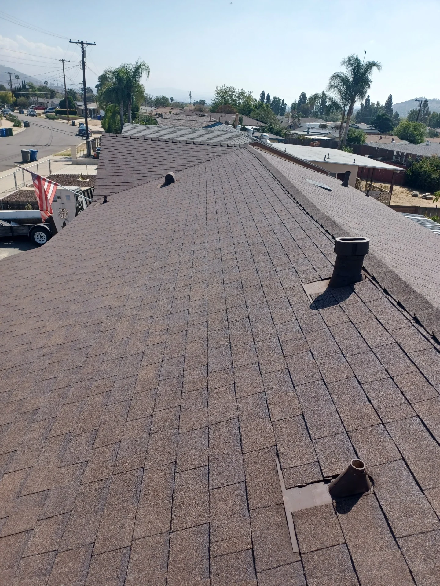 Newly installed gray asphalt shingle roof on commercial building with vent pipes