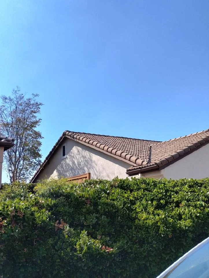 Spanish tile roof with clay barrel tiles on stucco home with clear blue sky