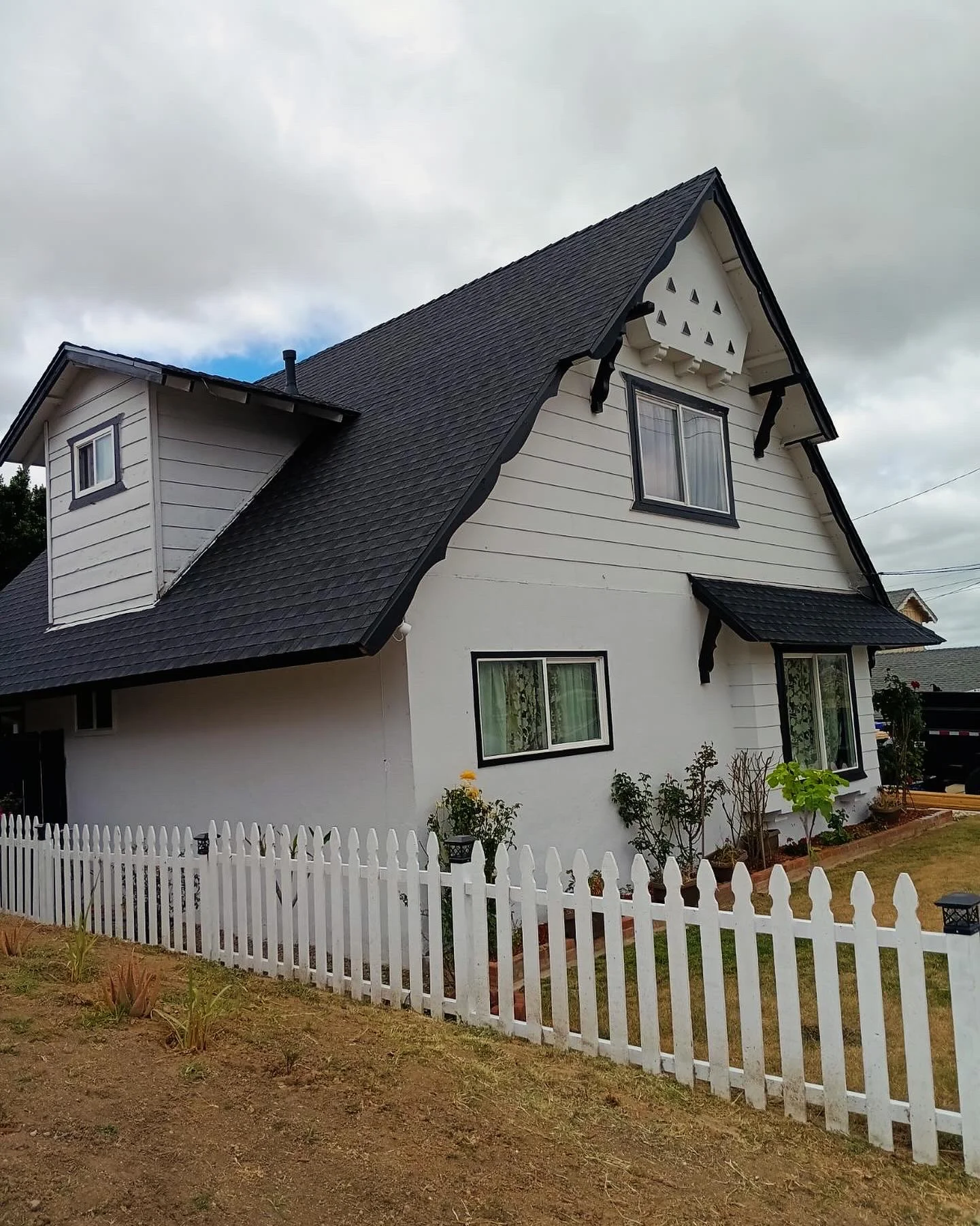 Two-story home with new charcoal gray architectural shingle roof and white picket fence
