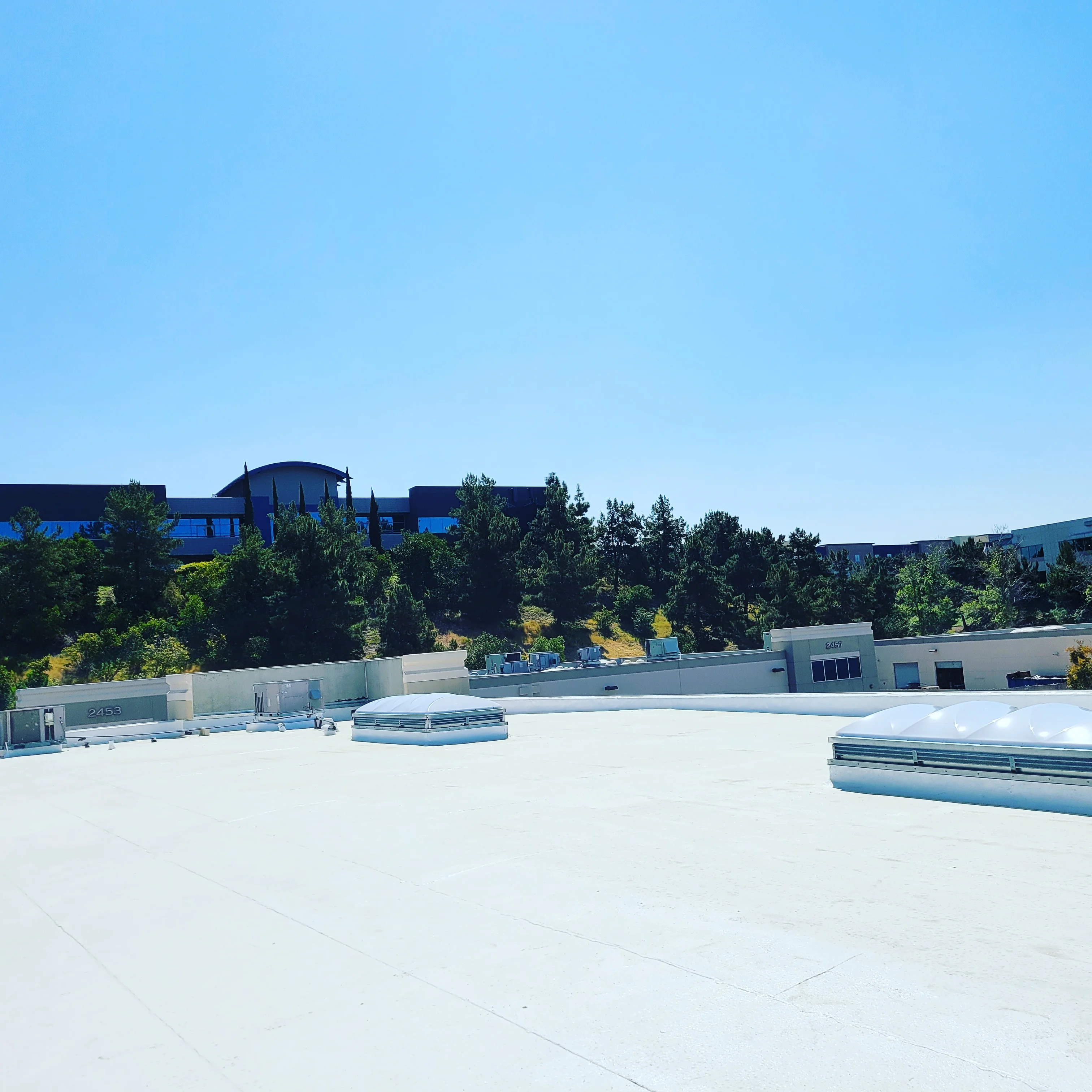 White membrane flat roof installation on commercial building with HVAC units and skylights