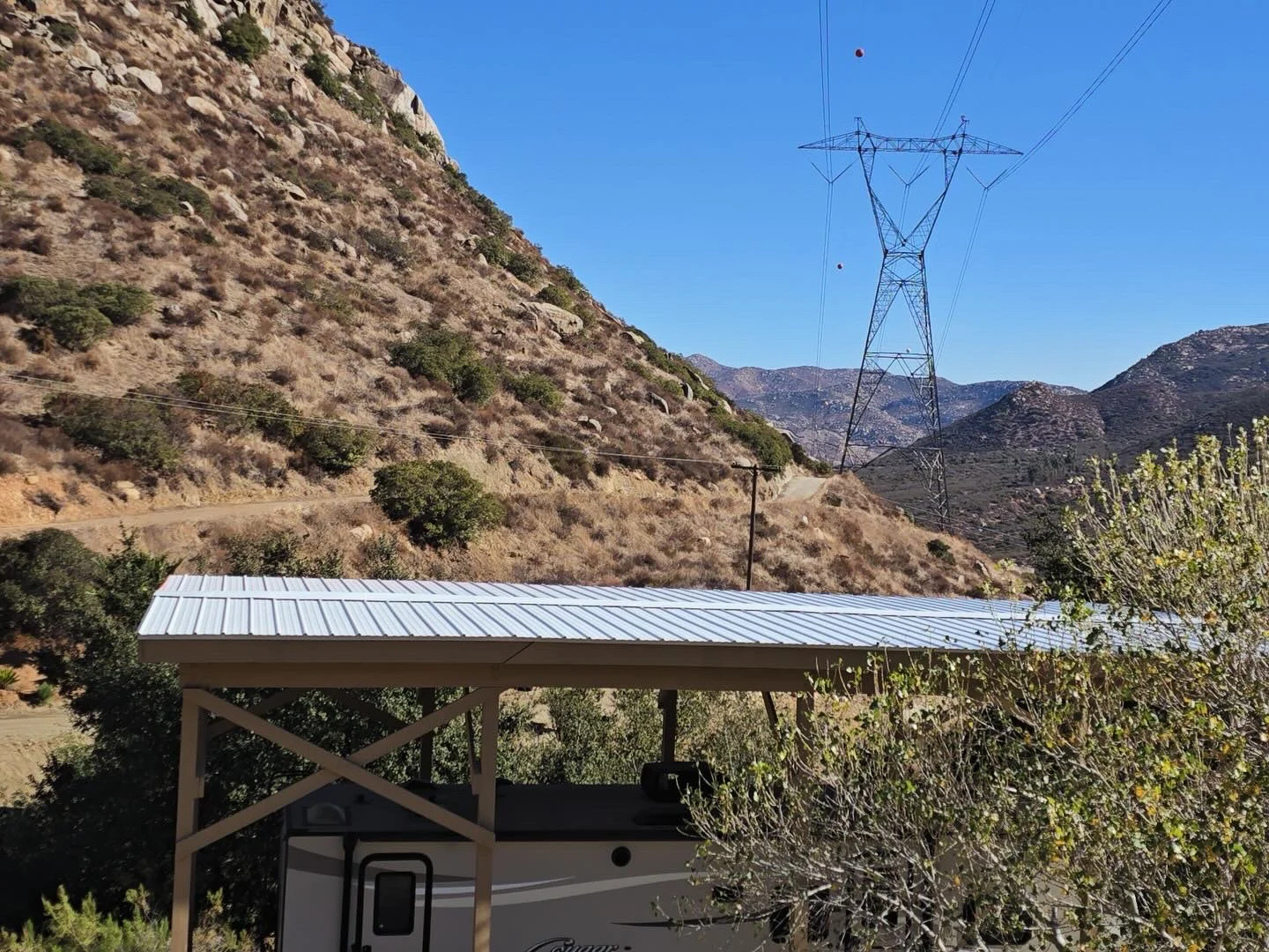 Metal carport roof with standing seam design covering RV shelter in hillside landscape