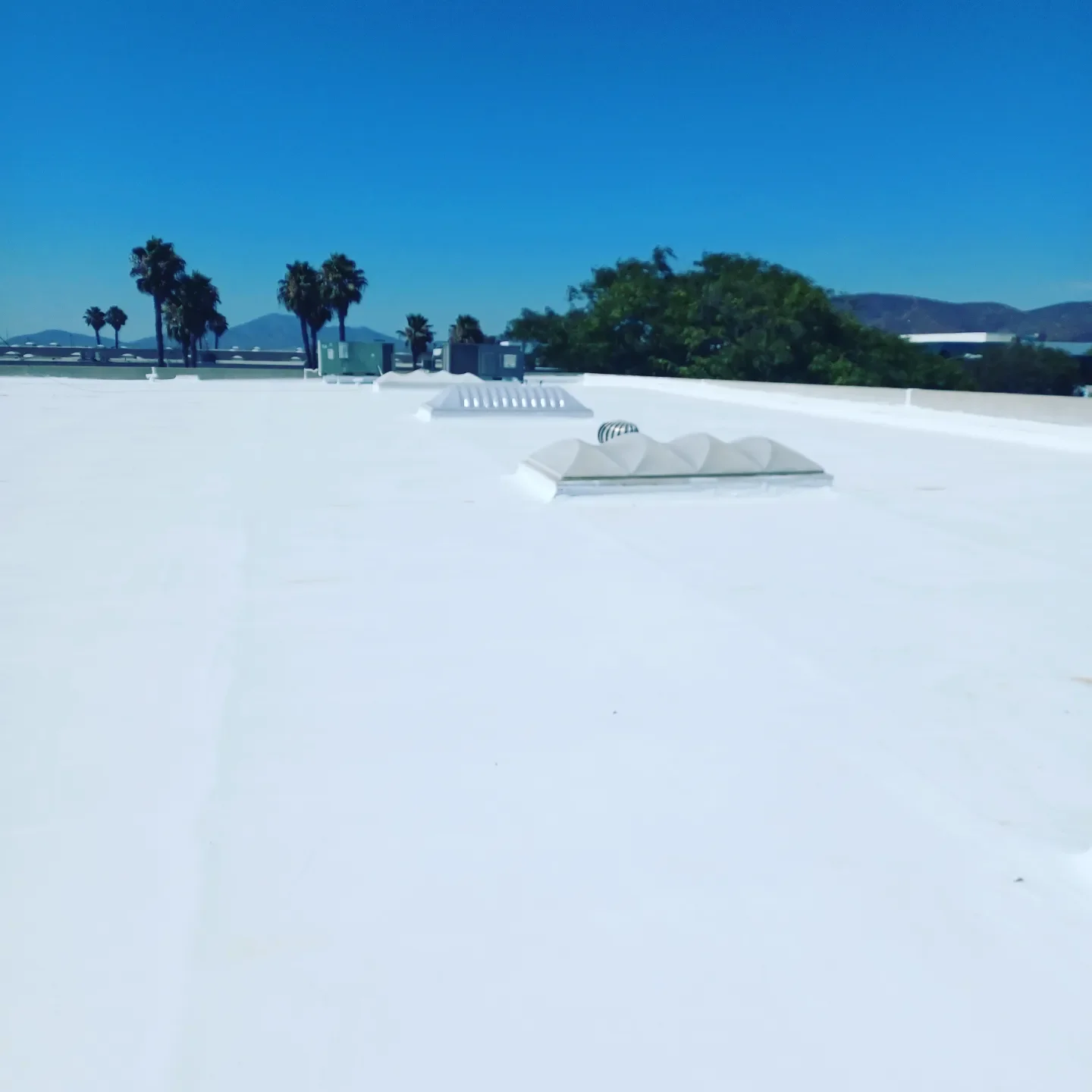 White commercial flat roof with HVAC vents and membrane system installation