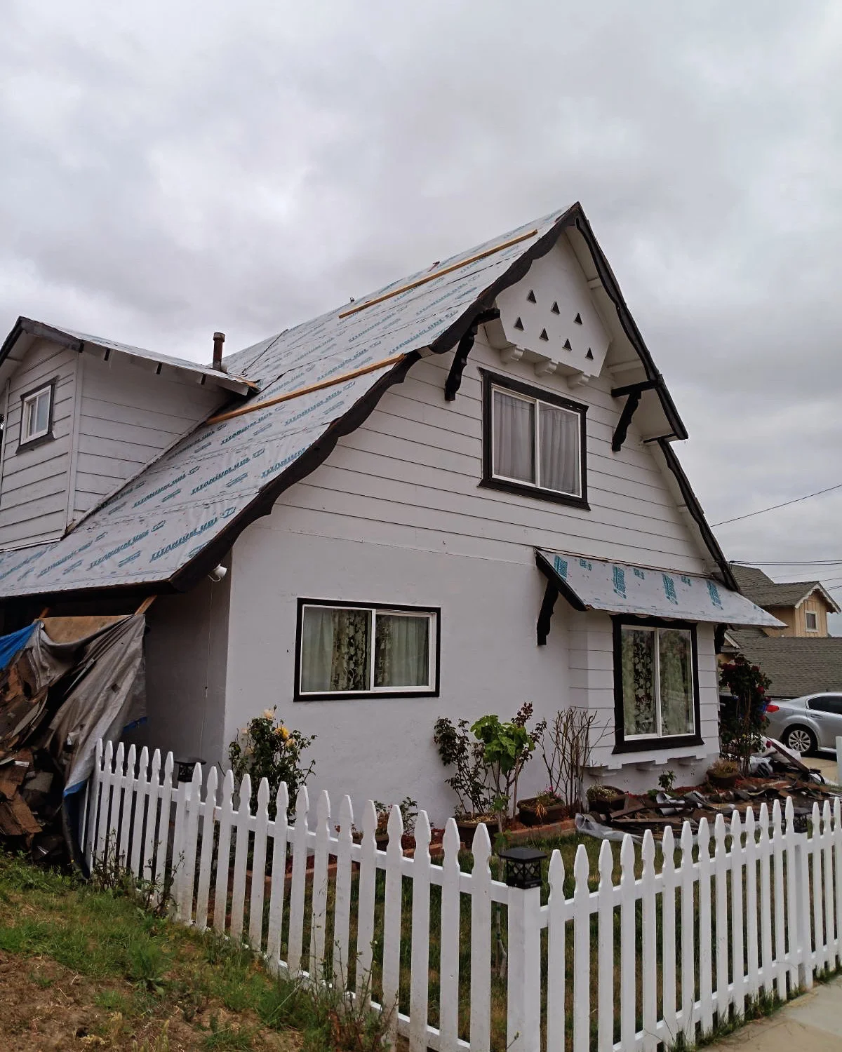 Residential home with new roof installation showing blue underlayment and black shingles