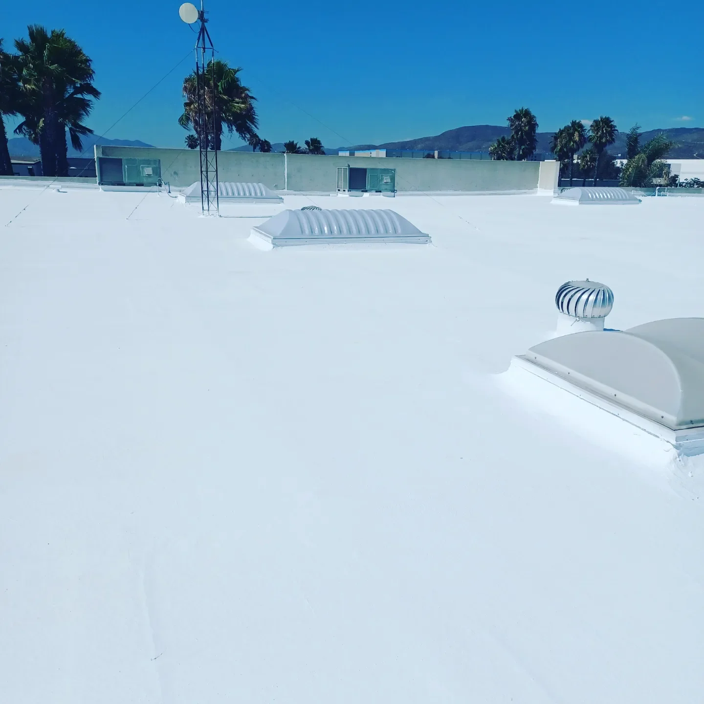 White commercial flat roof with HVAC vents and metal rooftop equipment installed